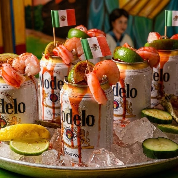 Modelo beer cans with shrimp, lime, and Mexican flags on ice with oysters and cucumbers.